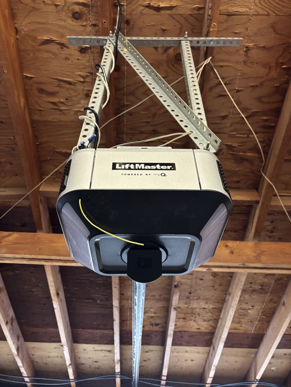 LiftMaster garage door opener mounted on ceiling with visible wiring and support brackets.