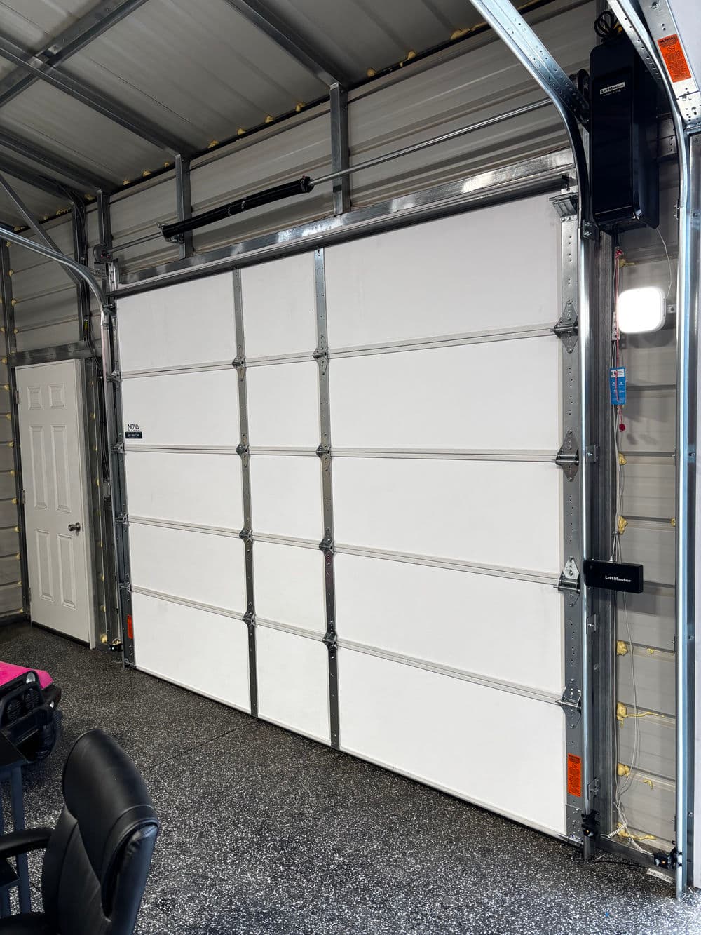 Modern garage interior with a large white sectional door and gray floor. Ideal for storage solutions.