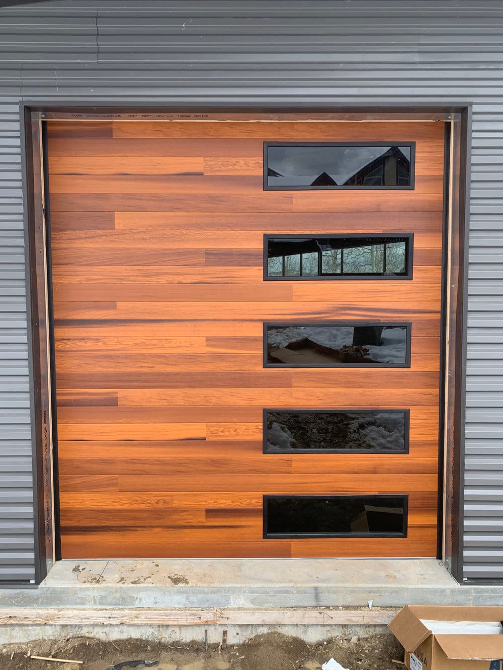 Modern wooden garage door with four windows, showcasing sleek design and craftsmanship.