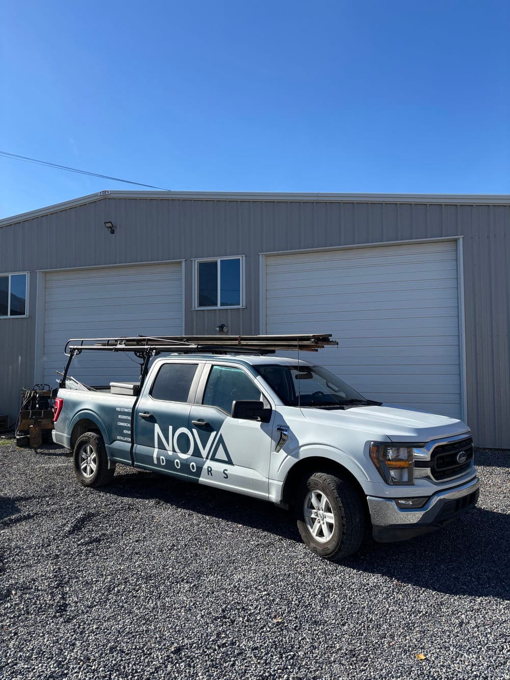 Nova Doors truck parked outside a workshop under clear blue skies.