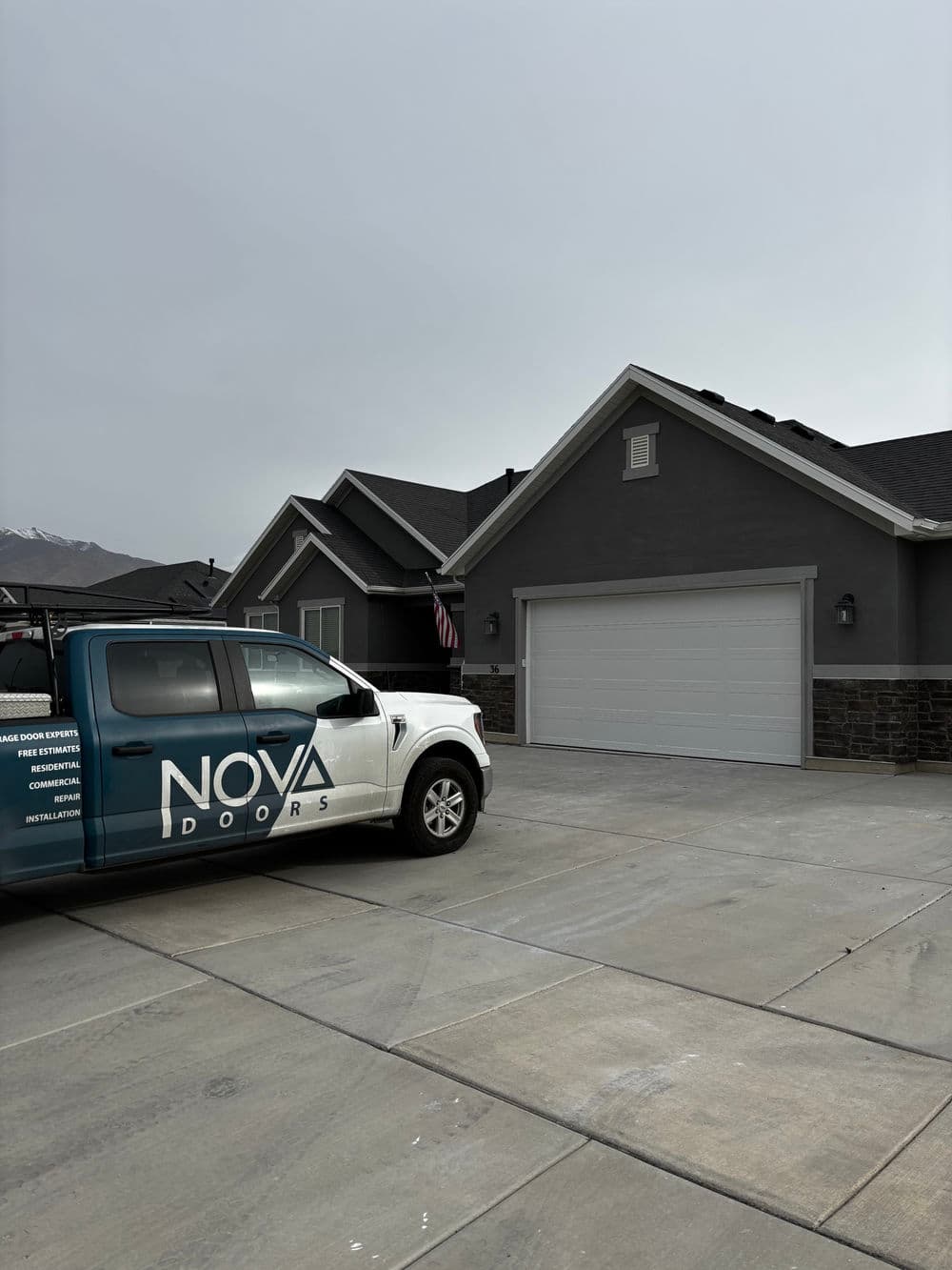 NOVA Doors truck parked in front of a modern gray house with a garage.