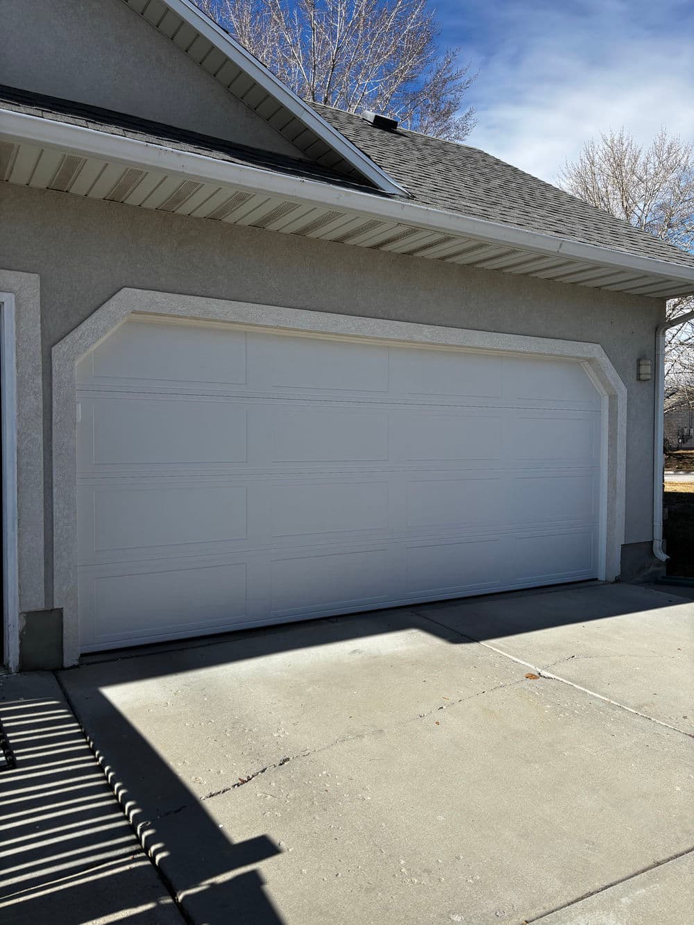 White garage door on a residential house with a clear blue sky in the background.