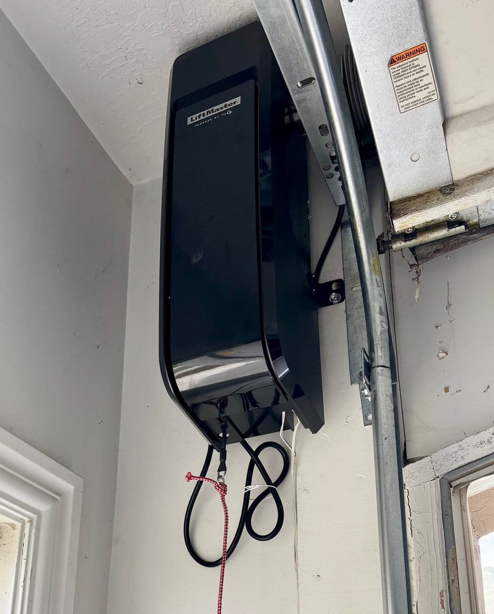 Modern electric car charger mounted on garage wall, featuring sleek black design.