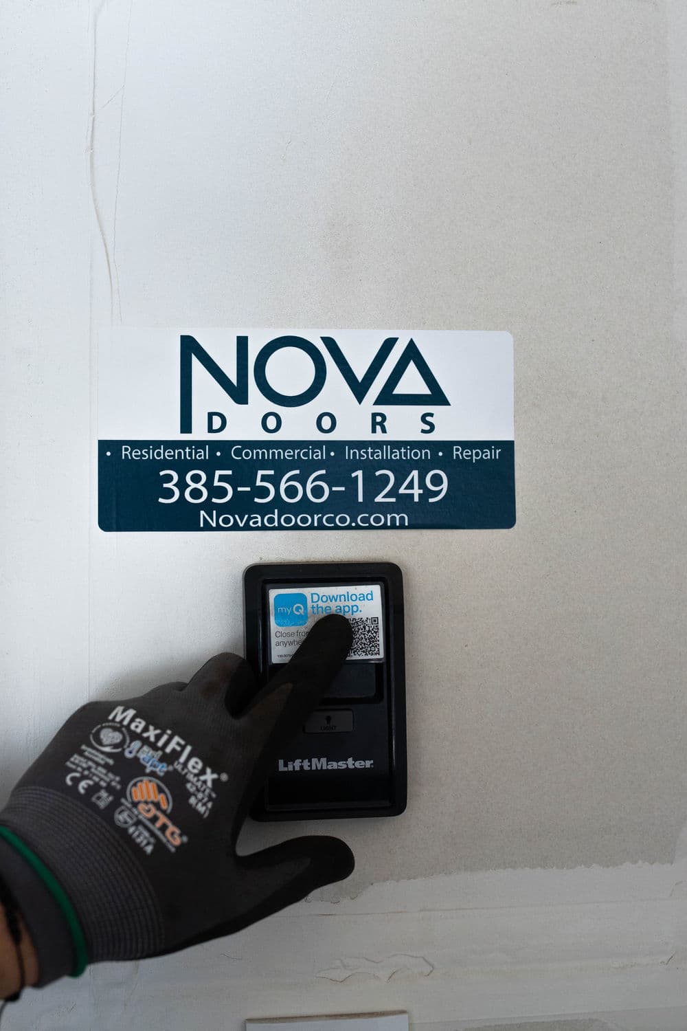 Hand pressing LiftMaster control on NOVA Doors service vehicle, featuring contact details.