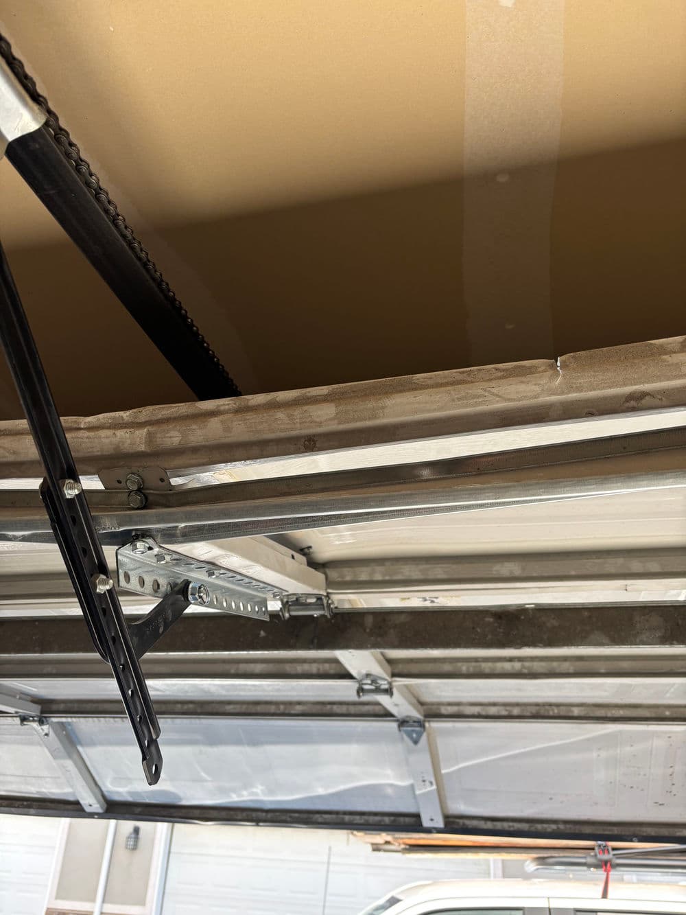 Overhead garage door mechanism with metal frame and chain drive system.