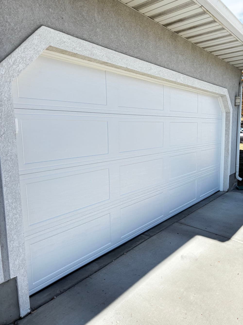 White garage door with modern design, installed on a residential building exterior.