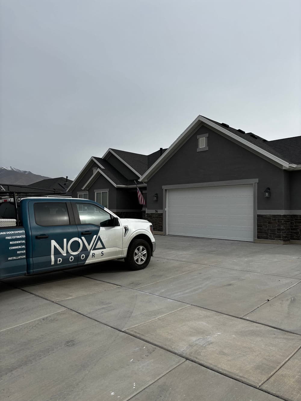 NOVA Doors truck parked in front of a modern home with a garage door.