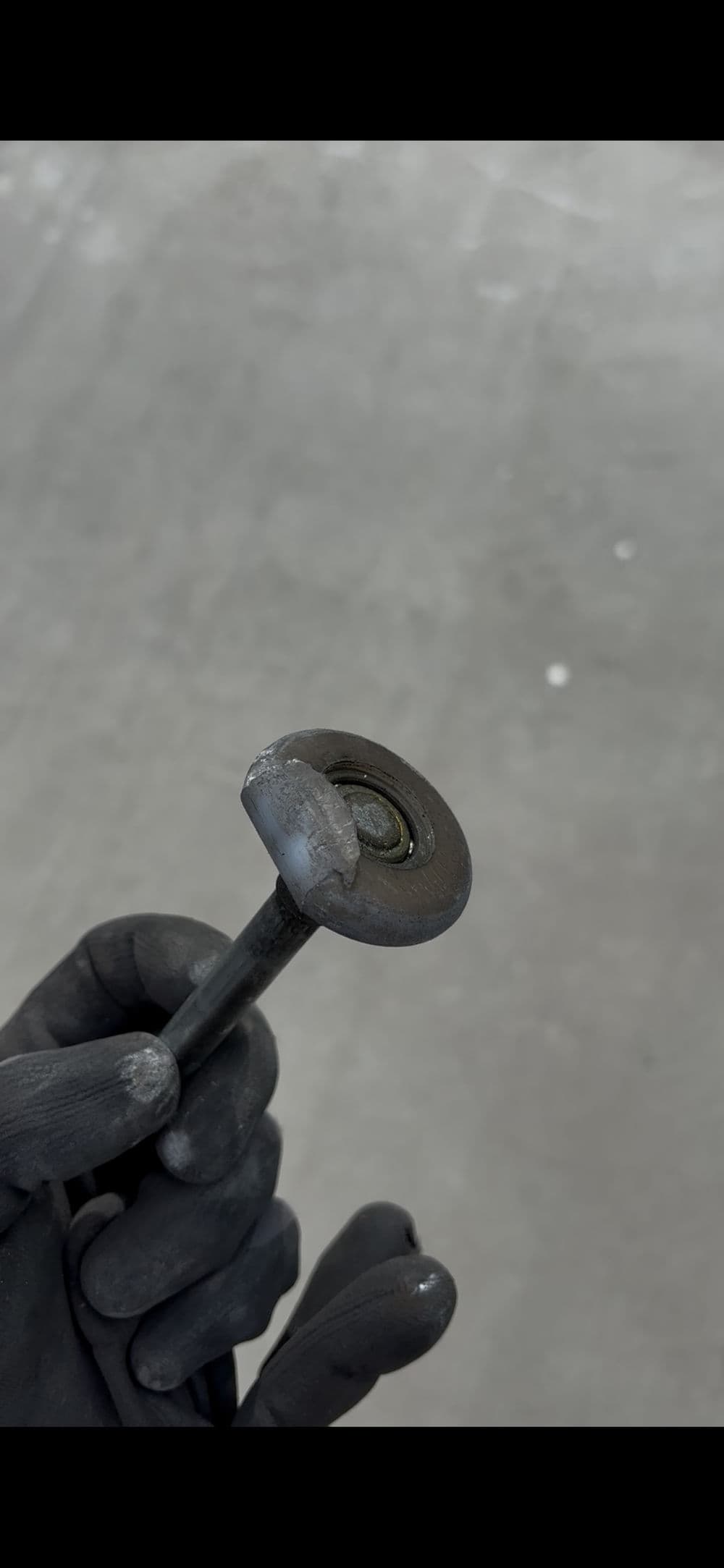 Close-up of a hand holding a worn out mechanical part, showcasing rust and wear details.