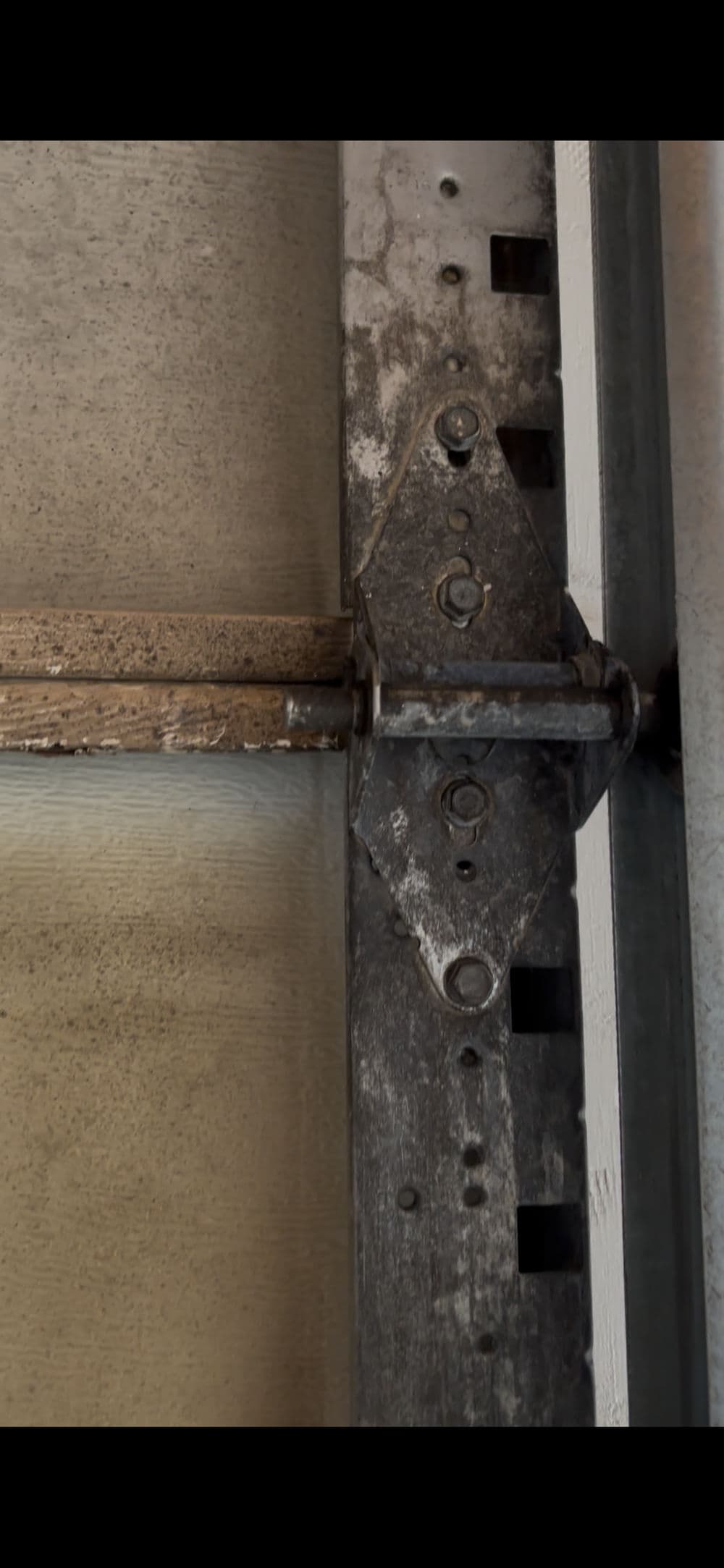 Close-up of a metal garage door hinge with rust and wear details.