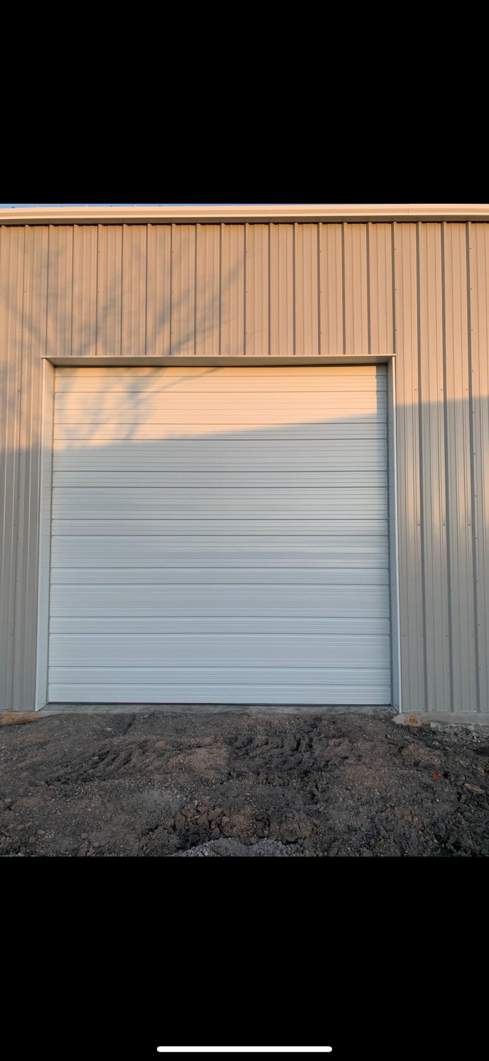 Metal garage door on a storage building with a gravel base and soft natural lighting.