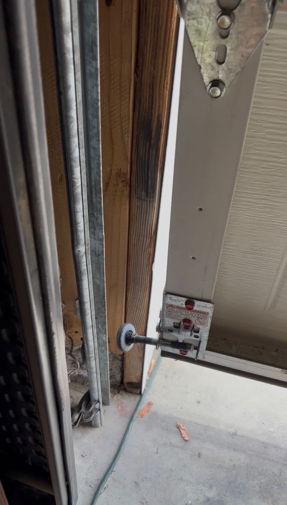 Close-up of a garage door latch and track, showing wooden frame and metal components.
