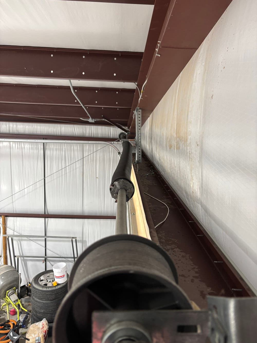 Close-up of a pulley system mounted on steel beams in a warehouse setting.