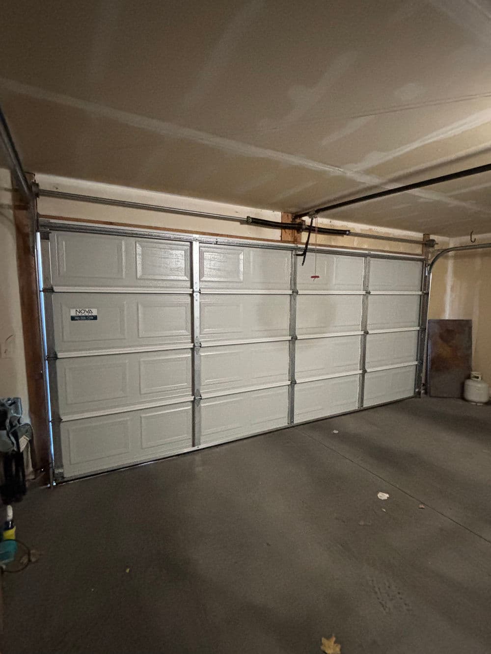 White garage door in a spacious garage with concrete flooring and unfinished walls.