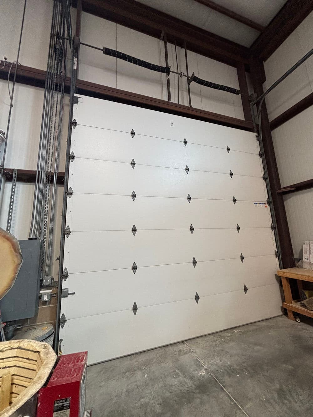 White industrial garage door with decorative hardware in a metal building interior.