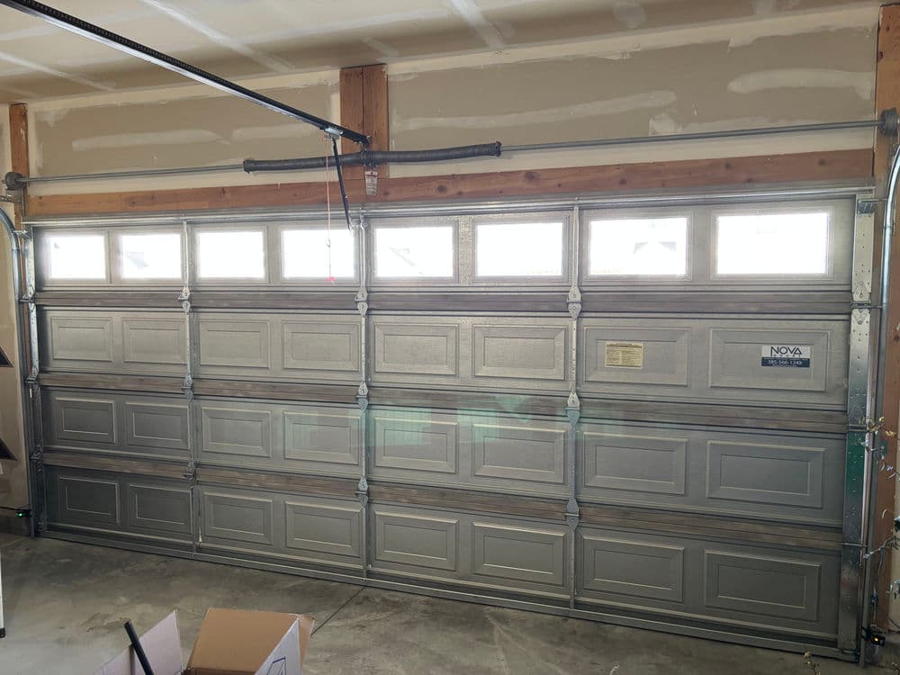 Silver garage door with windows, installed in a residential garage setting.