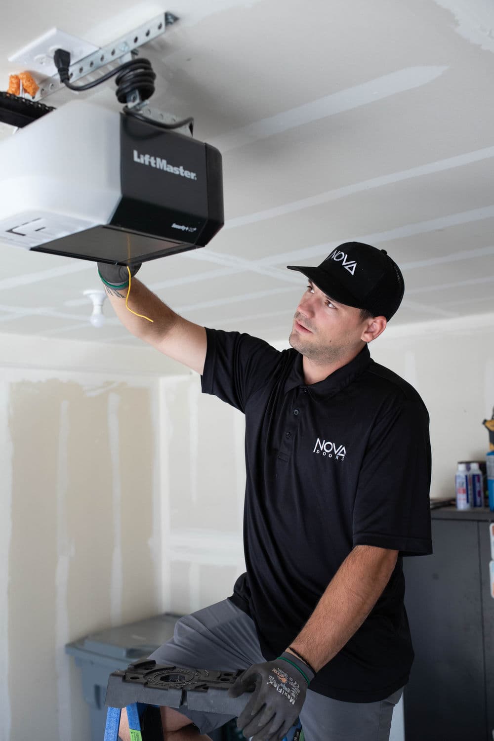 Technician installing LiftMaster garage door opener in residential garage setting.