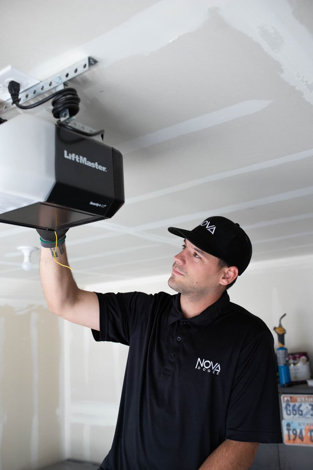 Technician installing a LiftMaster garage door opener in a residential garage.